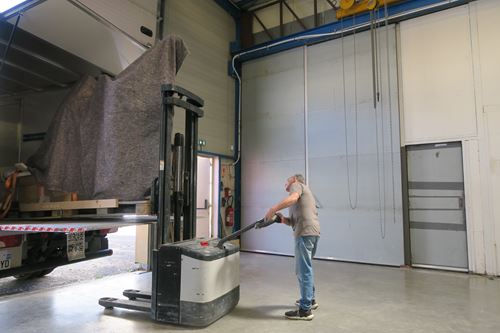 Déchargement d'une sculpture grand format d'un camion dans l'espace atelier